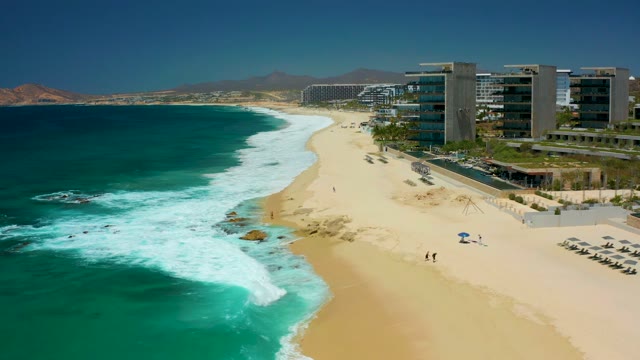 DREAMS LOS CABOS BCS MEXICO-2021: Beachgoers Walking Along Sandy Shore with Ocean Waves