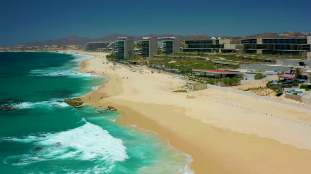DREAMS LOS CABOS BCS MEXICO-2021: Waves Rolling Onto Sandy Beach with Coastal Buildings