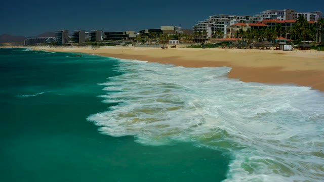 DREAMS LOS CABOS BCS MEXICO-2021: Waves Crashing Onto Sandy Beach with Coastal Buildings