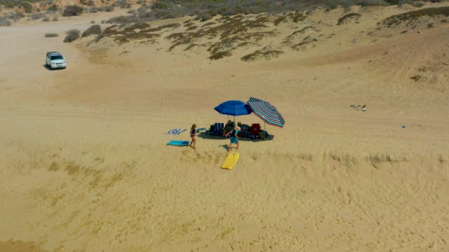 SHIPWRECKS LOS CABOS BCS MEXICO-2021: Beachgoers with Surfboards Moving Toward Umbrellas