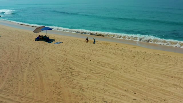 SHIPWRECKS LOS CABOS BCS MEXICO-2021: Two People Strolling on Sandy Beach by Turquoise Ocean