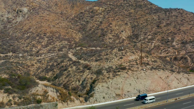 MARQUIS LOS CABOS MEXICO-2021: Vehicles Moving Along Mountain Road in Arid Landscape