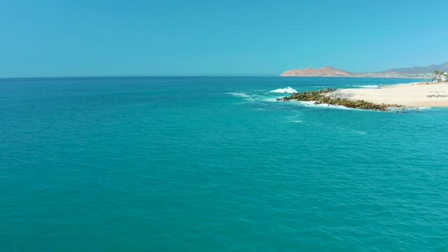 MARQUIS LOS CABOS MEXICO-2021: Ocean Waves Breaking on Sandy Beach with Rocky Outcrops