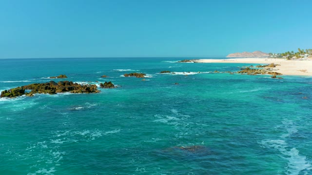 MARQUIS LOS CABOS MEXICO-2021: Waves Breaking on Rocky Ocean Outcrops Near Sandy Shore