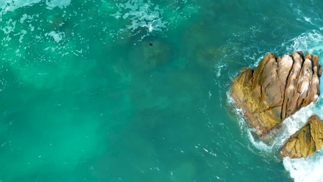 MARQUIS LOS CABOS MEXICO-2021: Swimmer in Turquoise Ocean Near Rocky Outcrop