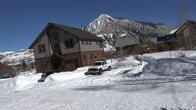 CRESTED BUTTE COLORADO-2015: White Truck Parked Near Tan And Brown House On A Clear Day
