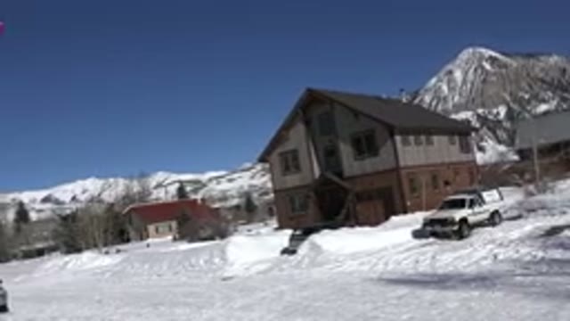 CRESTED BUTTE COLORADO-2015: Snow Covered Mountains And Tan Building On A Sunny Day