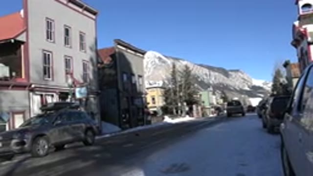 CRESTED BUTTE COLORADO-2015: Car Driving Slowly On Empty Snowy Road On A Clear Day