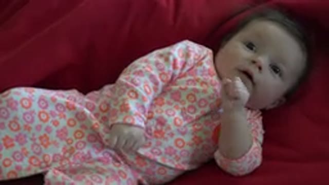 WESTMINSTER COLORADO-2015: Baby Wearing Orange and Pink Sleeper Lies on Red Blanket