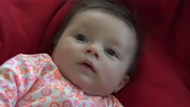 WESTMINSTER COLORADO-2015: Baby Wearing White Red and Orange Shirt Lies on Red Blanket