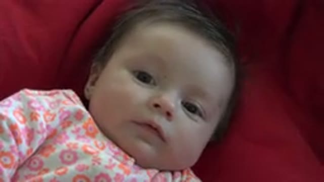 WESTMINSTER COLORADO-2015: Baby Wearing White Orange And Pink Sleeper Lies On Blanket