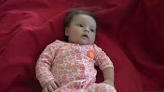 WESTMINSTER COLORADO-2015: A Baby Laying On A Red Blanket In A Pink Onesie