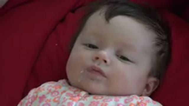 WESTMINSTER COLORADO-2015: Little Baby Laying On Her Back On A Red Comforter And