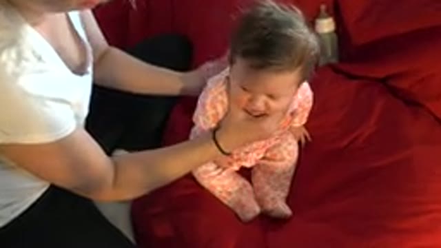 WESTMINSTER COLORADO-2015: Woman Patting Baby On The Back Sitting On Red Sofa