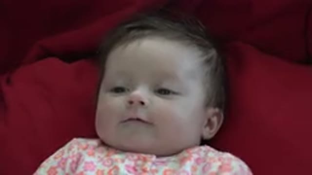 WESTMINSTER COLORADO-2015: Pale Baby With Dark Hair On Red Bedding Waving Arms