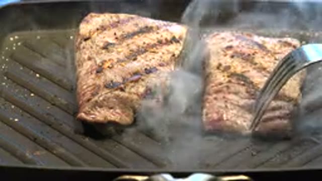 WESTMINSTER COLORADO-2015: Off Screen Person Turns Steak Cooking On Gray In Door