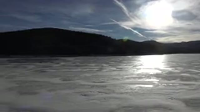 NEDERLAND COLORADO-2015: Sun Shining Through Clouds Over Foamy Water With Hills
