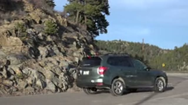 NEDERLAND COLORADO-2015: SUV Crossing Mountain Road With A Rocky Hillside In