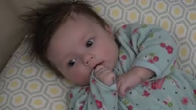 WESTMINSTER COLORADO-2015: Baby Wearing Blue and Red Sleeper Lies on Pale Blue Cushion