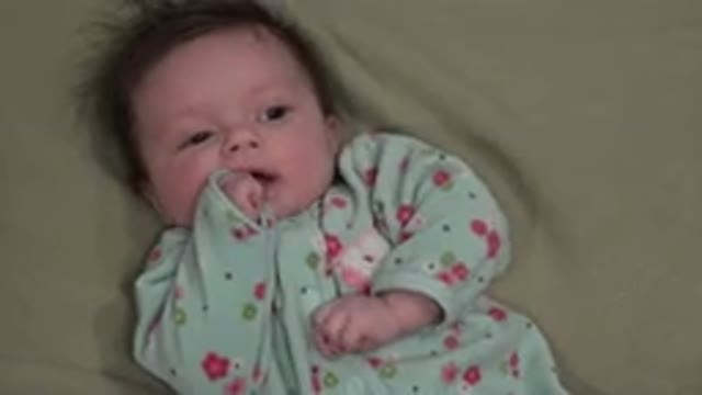 WESTMINSTER COLORADO-2015: Infant Wearing Blue and Red Sleeper Lies on Green Blanket