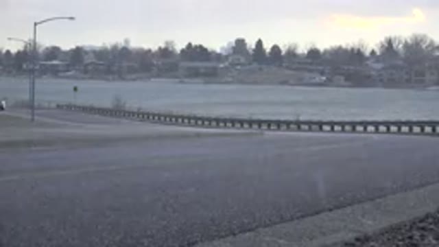 WESTMINSTER COLORADO-2015: Car Travels Down A Road Beside A Lake On A Rainy Day
