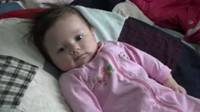 WESTMINSTER COLORADO-2015: Baby Wearing Pink Sleeper Lies On Patchwork Quilt