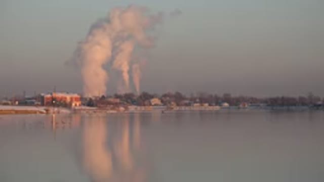 WESTMINSTER COLORADO-2015: A Factory Smoking Smoke On The Edge Of A Lake At Sunset