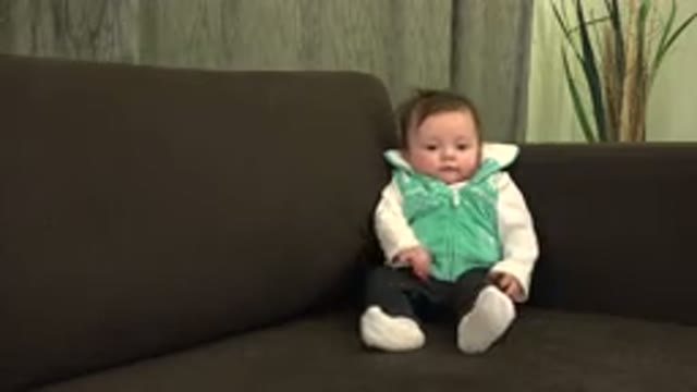WESTMINSTER COLORADO-2015: Baby in Green Sweater Sits and Plays on Brown Couch