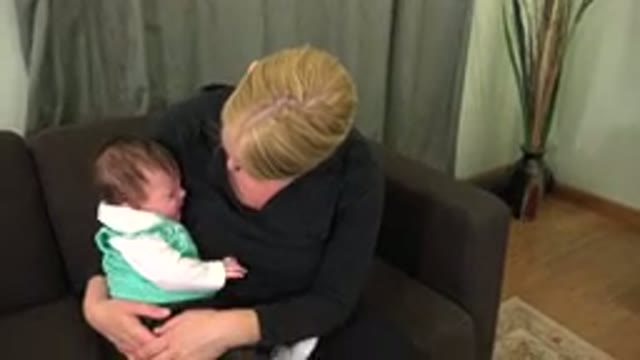 WESTMINSTER COLORADO-2015: Woman Wearing Black Shirt Sits On Brown Sofa Holding Baby