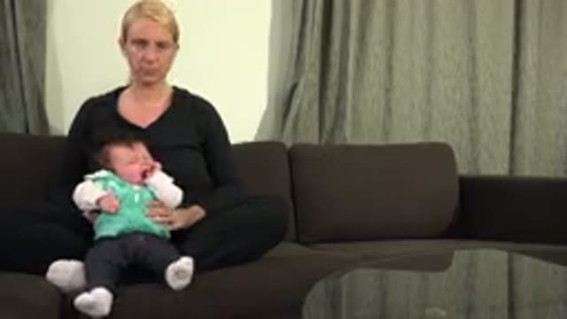 WESTMINSTER COLORADO-2015: Blonde Woman Sitting Cross-Legged On The Sofa Holding Baby
