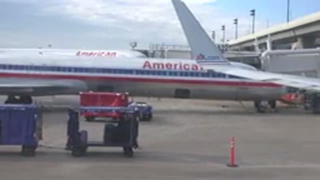PLAYA DEL CARMEN MEXICO-2015: Blue Luggage Cart Driving By Silver American Airline Plane
