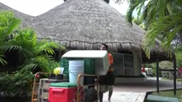 PLAYA DEL CARMEN MEXICO-2015: Two Men Pushing A Cart Full Of Junk In Front Of A Hut