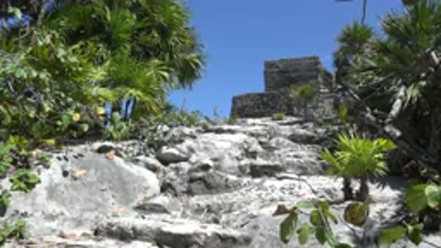 TULUM MEXICO-2015: A Woman Walking Across Rocks Toward a Temple Monument