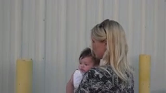 DENVER COLORADO-2015: Blonde Woman Facing Building Outdoors Turns and Reveals Baby