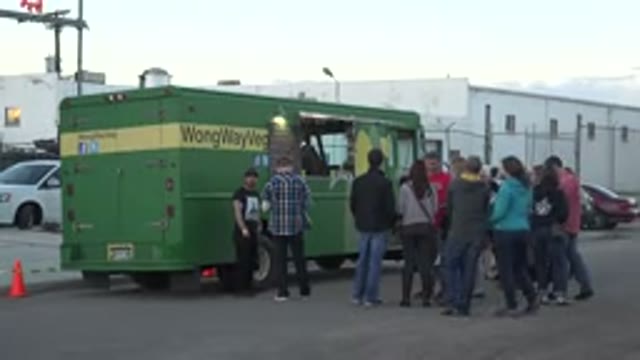 DENVER COLORADO-2015: Small Crowd Gathers Near Green Truck On A Clear Day