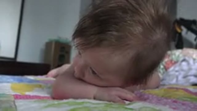 WESTMINSTER COLORADO-2015: Baby Lying On Pink And Green Quilt Looks At Camera