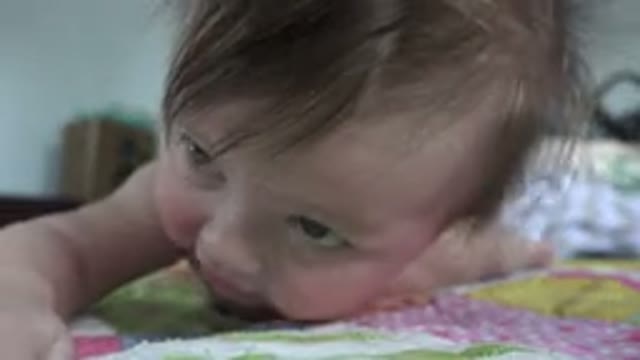 WESTMINSTER COLORADO-2015: A Cheerful Baby Lying On A Bed Reaching Its Arm Out