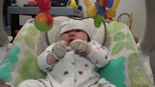 WESTMINSTER COLORADO-2015: Infant Wearing White Hat Sits in Green and White Baby Carrier