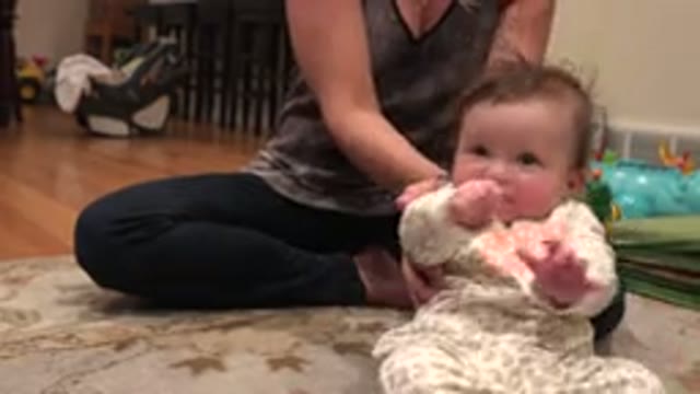 WESTMINSTER COLORADO-2015: A Mother Lowers Her Infant From A Sitting Position To Lying On Rug