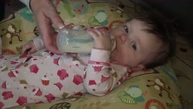 HIDDEN LAKE COLORADO-2015: Baby Lying Suckling Bottle Looking at Person on Bed