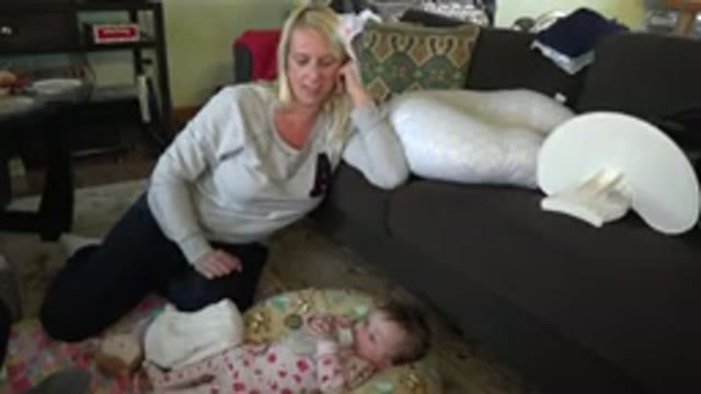 HIDDEN LAKE COLORADO-2015: Blonde Woman Smiling At Baby Drinking Milk On The Floor