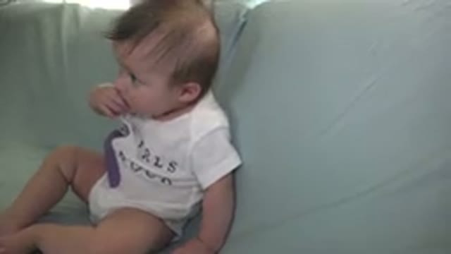 WESTMINSTER COLORADO-2015: Baby Wearing White Shirt Sits On Green Sofa Sucking Fingers