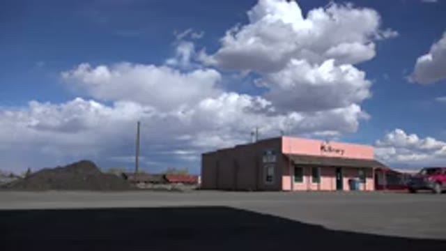 STERLING COLORADO-2015: Red Truck Driving Past Pink Library Building On A Sunny