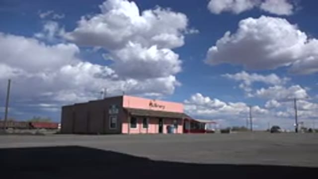 STERLING COLORADO-2015: Car Driving Past Store On A Sunny Hot Deserted Road