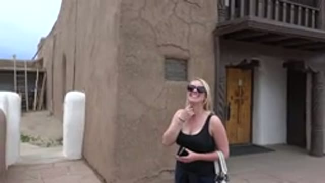 TAOS NEW MEXICO-2015: A Blonde Woman In Black And Sunglasses In Front Of An Old Building