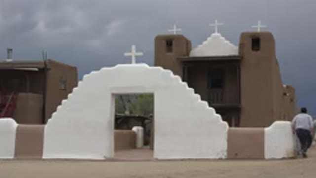 TAOS NEW MEXICO-2015: Tan And White Adobe Chapel On A Cloudy Day