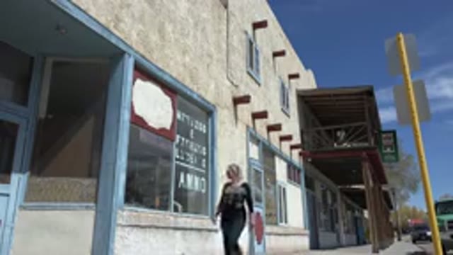 TAOS NEW MEXICO-2015: A Woman Walks Casually Near a Set of Stores