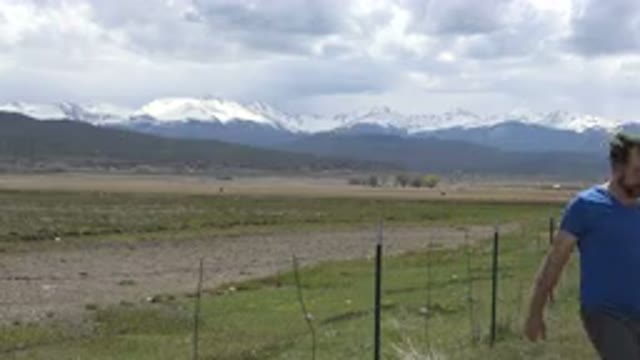 TAOS NEW MEXICO-2015: Couple Walking In Front Of Large Field And Mountains
