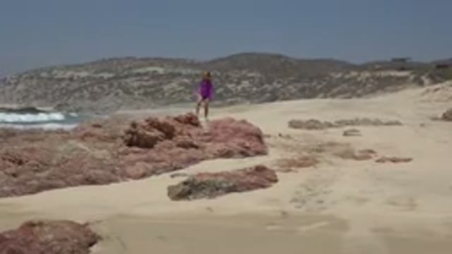 CABO SAN LUCAS MEXICO-2019: A Little Girl In Pink Dress Walking On Rocks On Beach