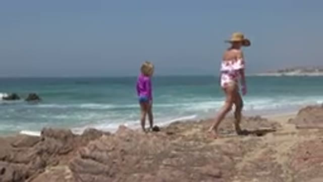 CABO SAN LUCAS MEXICO-2019: Woman In Hat Walks With Child On Beach Stones In The